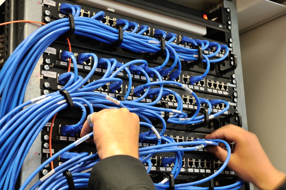 Man connecting network cables to switches Man connecting network cables to switches